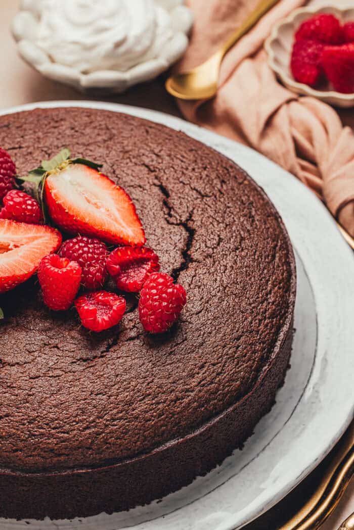 The baked chocolate ricotta cake on a platter with fresh fruit.