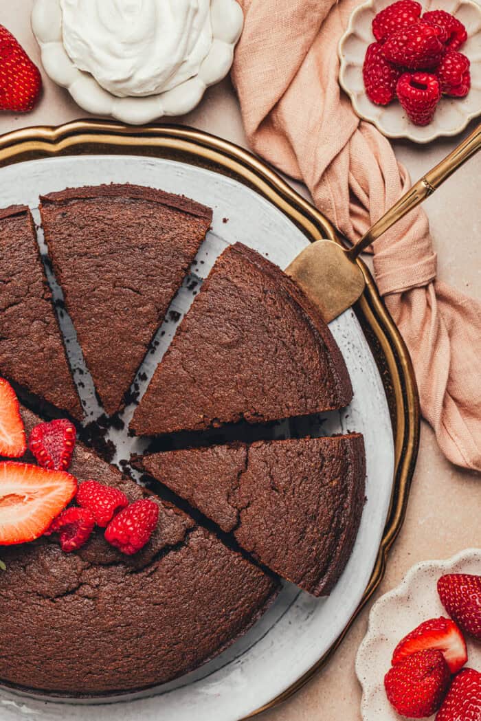 The baked chocolate ricotta cake, cut into slices on a platter with fresh fruit.