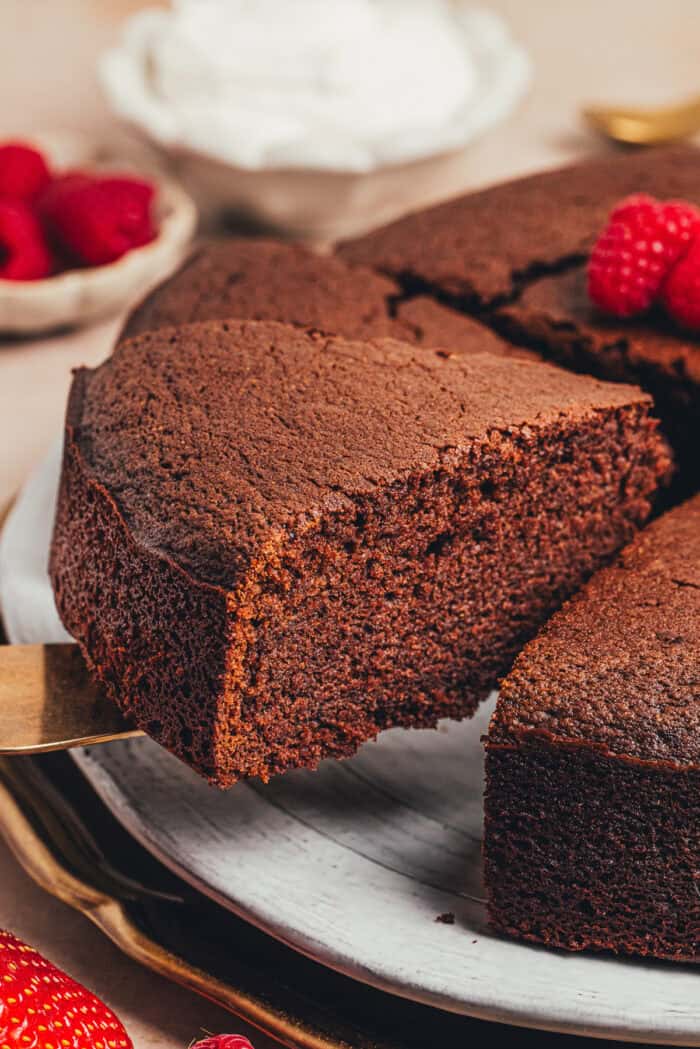 A slice of chocolate ricotta cake being lifted off of a platter.