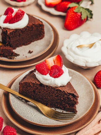 A slice of chocolate ricotta cake with whipped cream and berries on a plate.