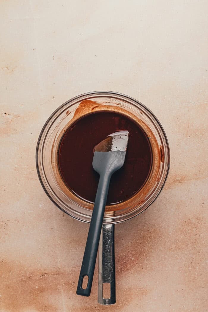 The butter and chocolate melted in a glass bowl with a spatula.