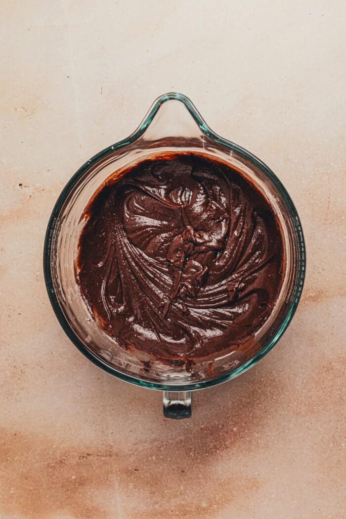The dry ingredients added to the wet ingredients in a large glass mixing bowl.