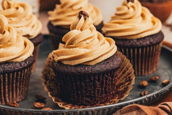 A chocolate cupcake with the cupcake liner being removed.