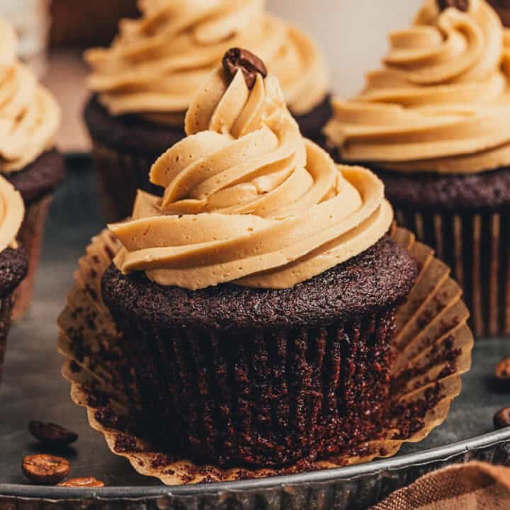 A chocolate cupcake with the cupcake liner being removed.