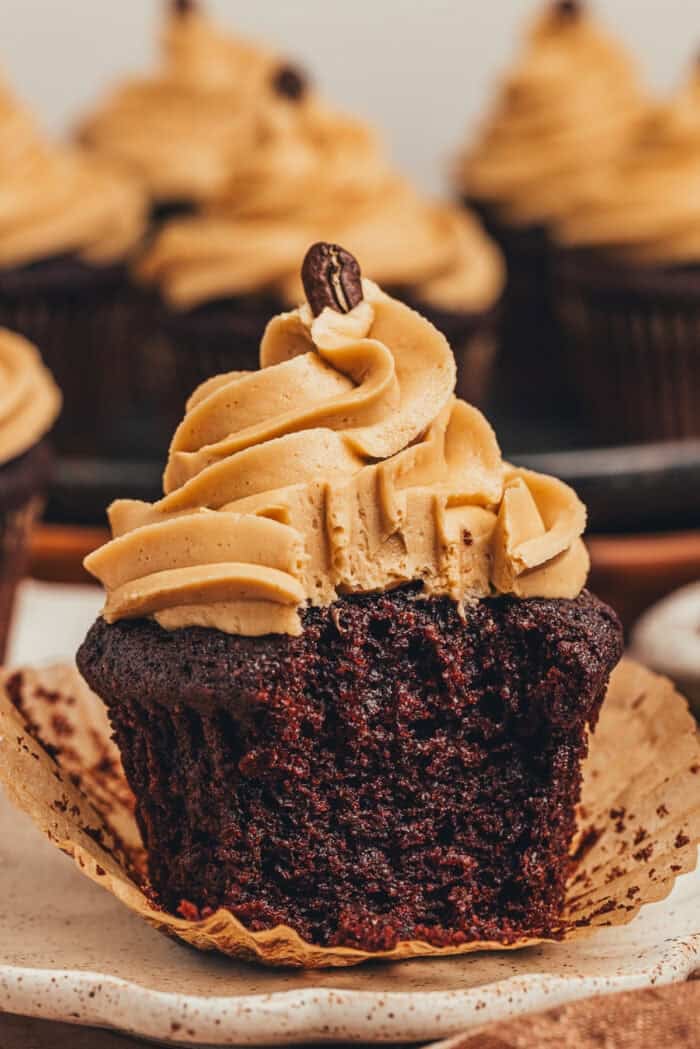 A chocolate cupcake with a bite taken out of it on a plate.