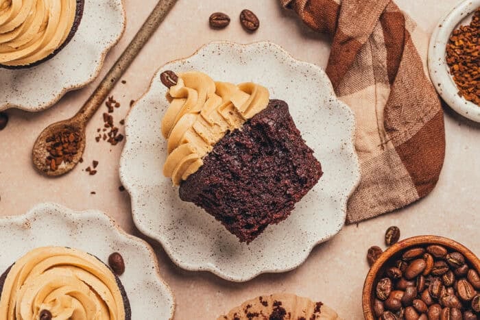 A chocolate cupcake with a bite taken out of it on a plate.