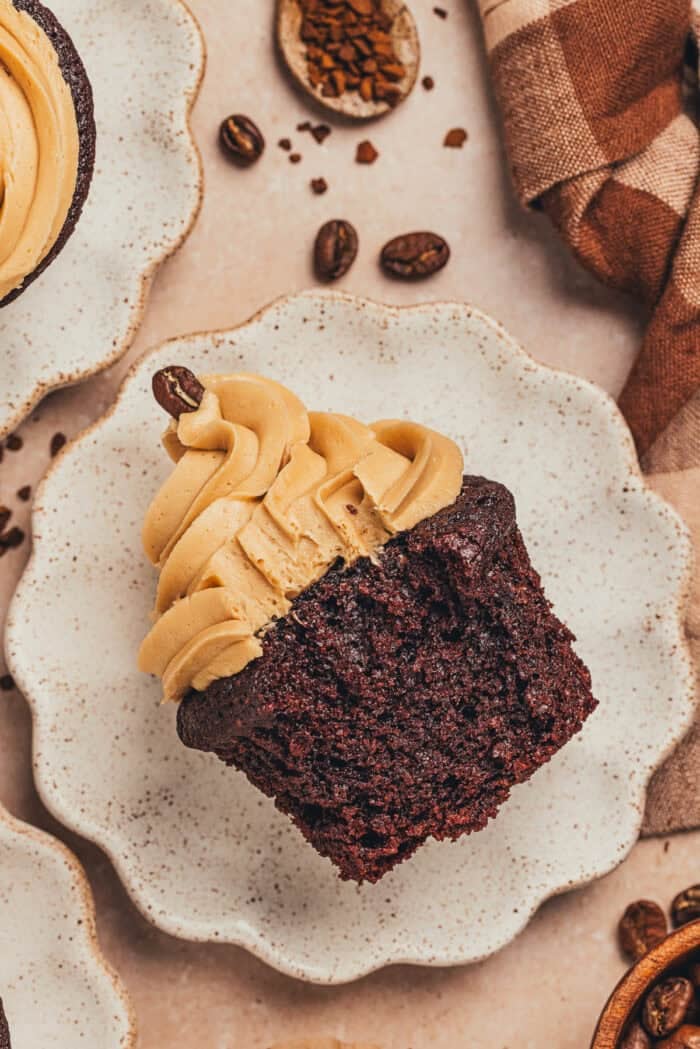 A chocolate cupcake with a bite taken out of it on a plate.