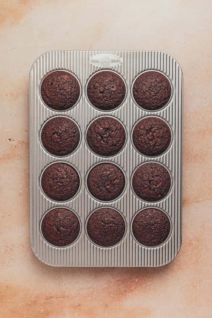 Baked chocolate cupcakes in a cupcake pan.