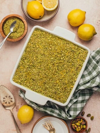 A square pan with pistachio tiramisu and lemons and a green checkered towel.