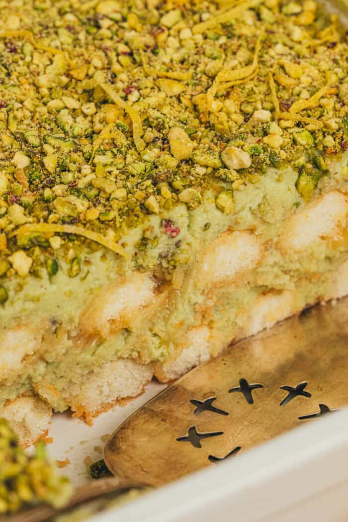 A side view of the tiramisu cake showing the lady fingers and layers of pistachio cream.