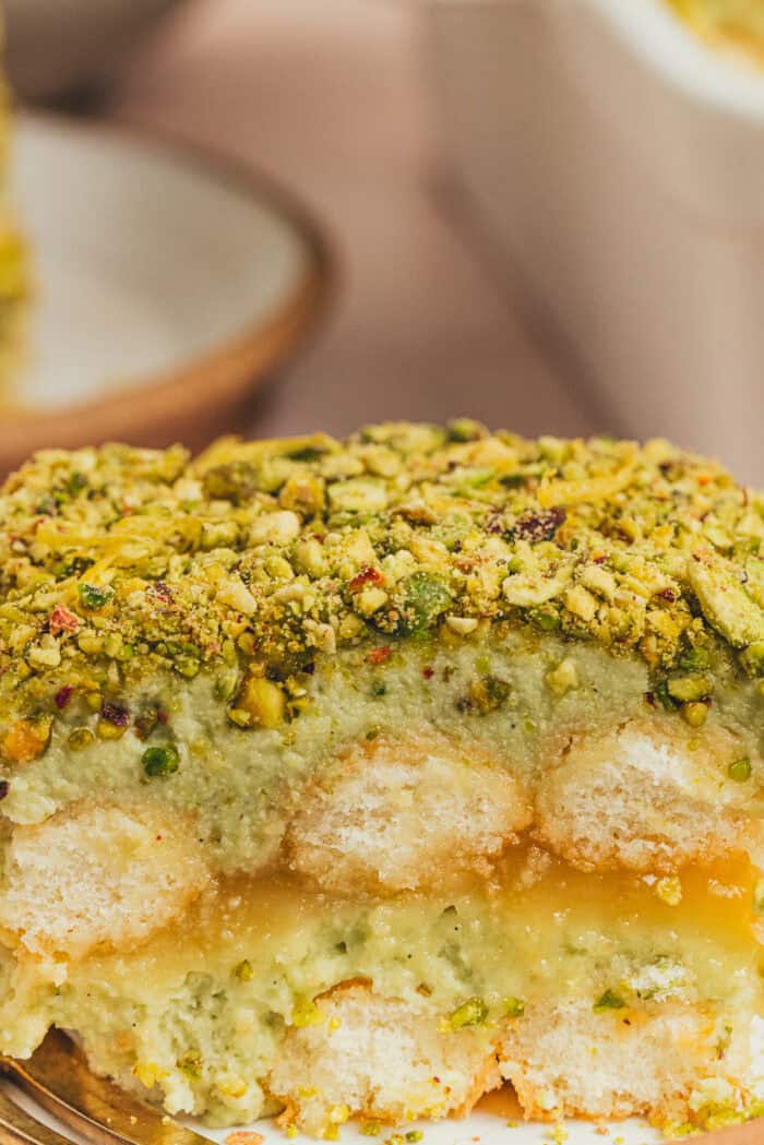 A side view of the tiramisu cake showing the lady fingers and layers of pistachio cream.