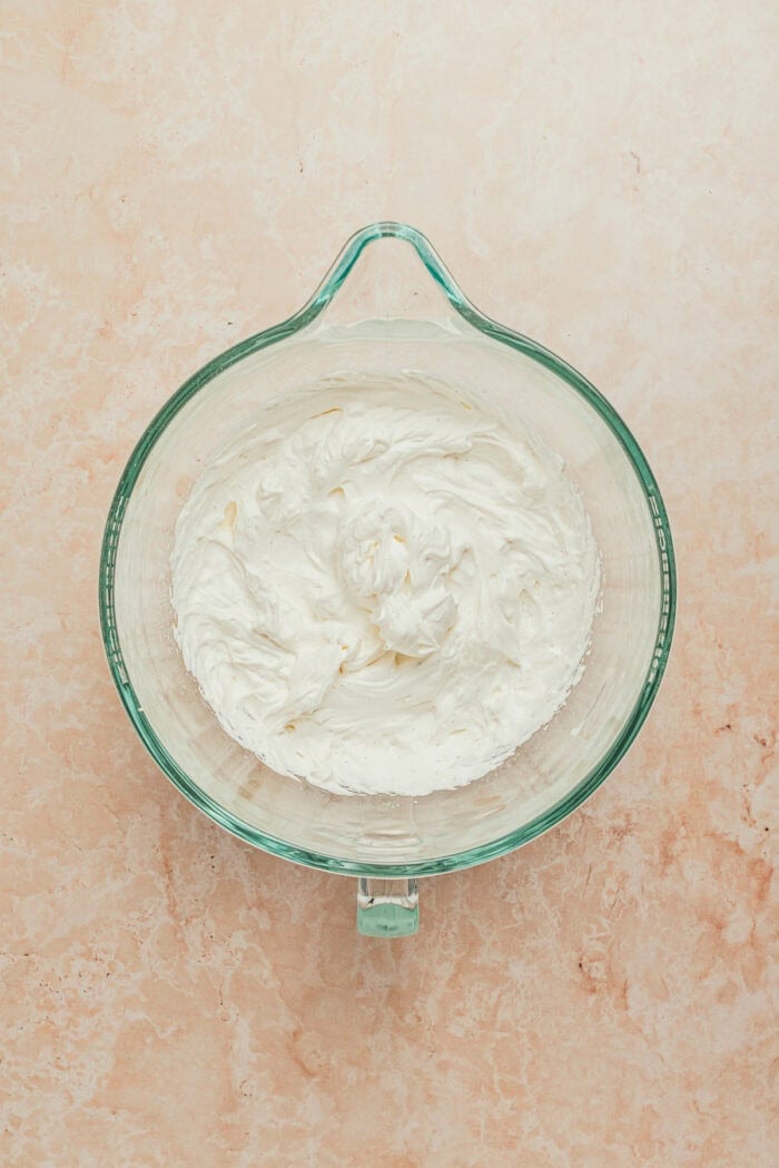 A glass mixing bowl with homemade whipped cream.