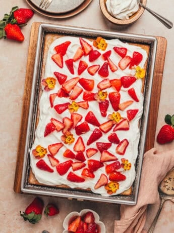 A rectangular cake pan with a tres leches cake with strawberries.