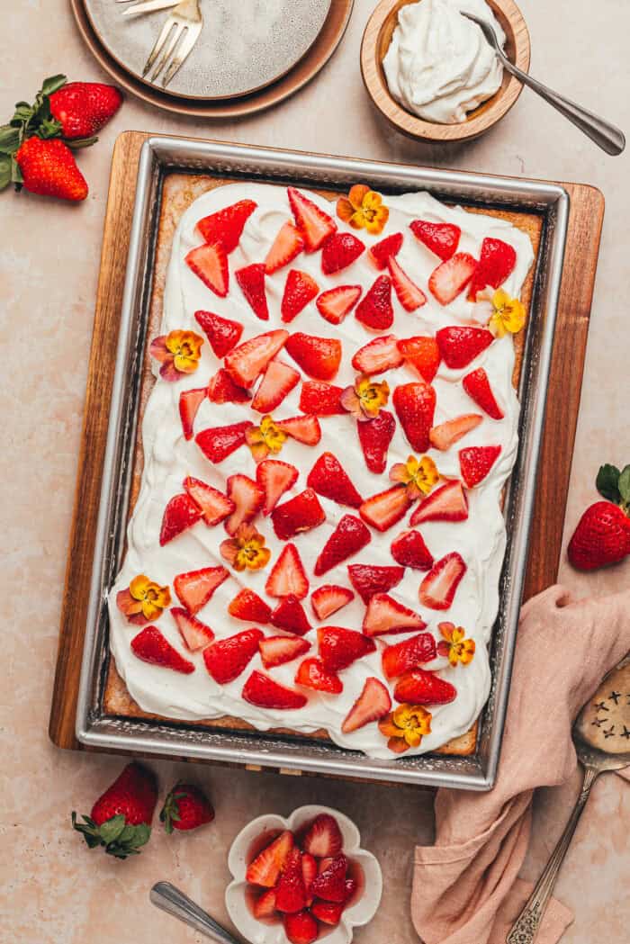 A rectangular cake pan with a tres leches cake with strawberries.