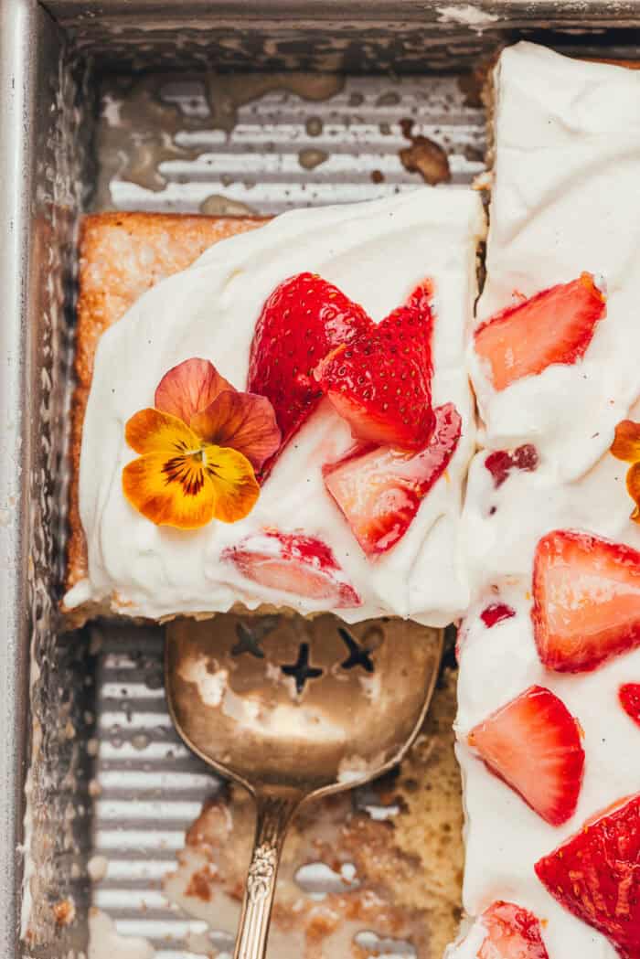 A cake pan with slices of strawberry tres leches cake.
