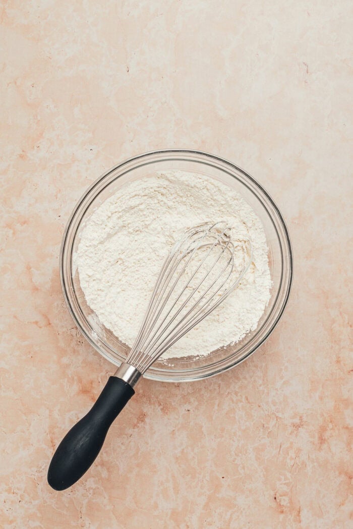 A glass bowl with the dry ingredients used to make strawberry tres leches cake.