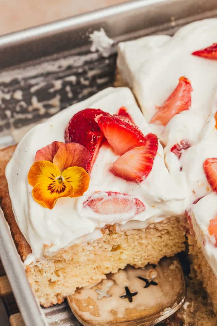 A cake pan with slices of strawberry tres leches cake.