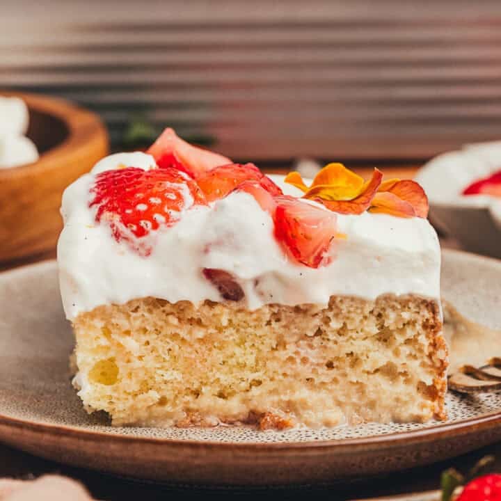 A slice of strawberry tres leches cake on a plate with a fork beside it.