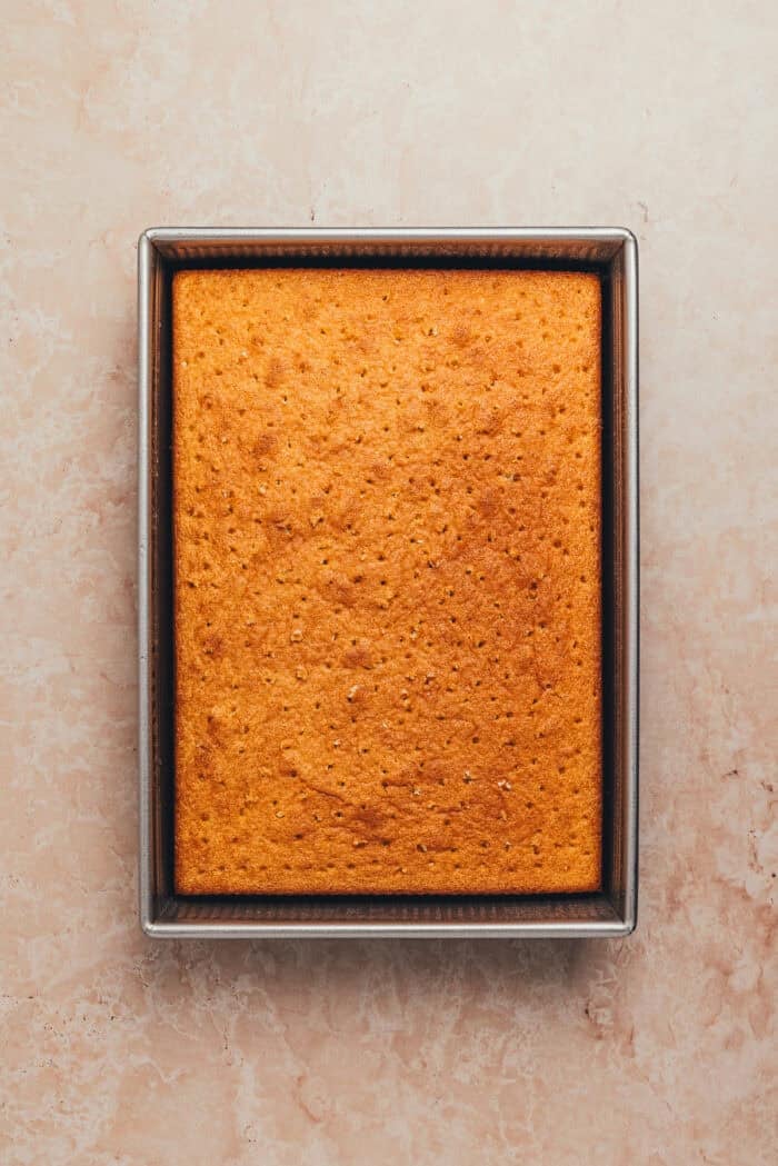 The baked tres leches cake with holes poked into it.