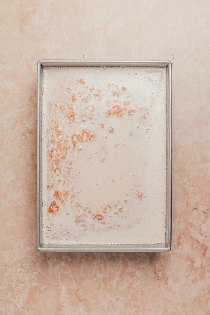 Homemade strawberry milk poured over the baked cake.