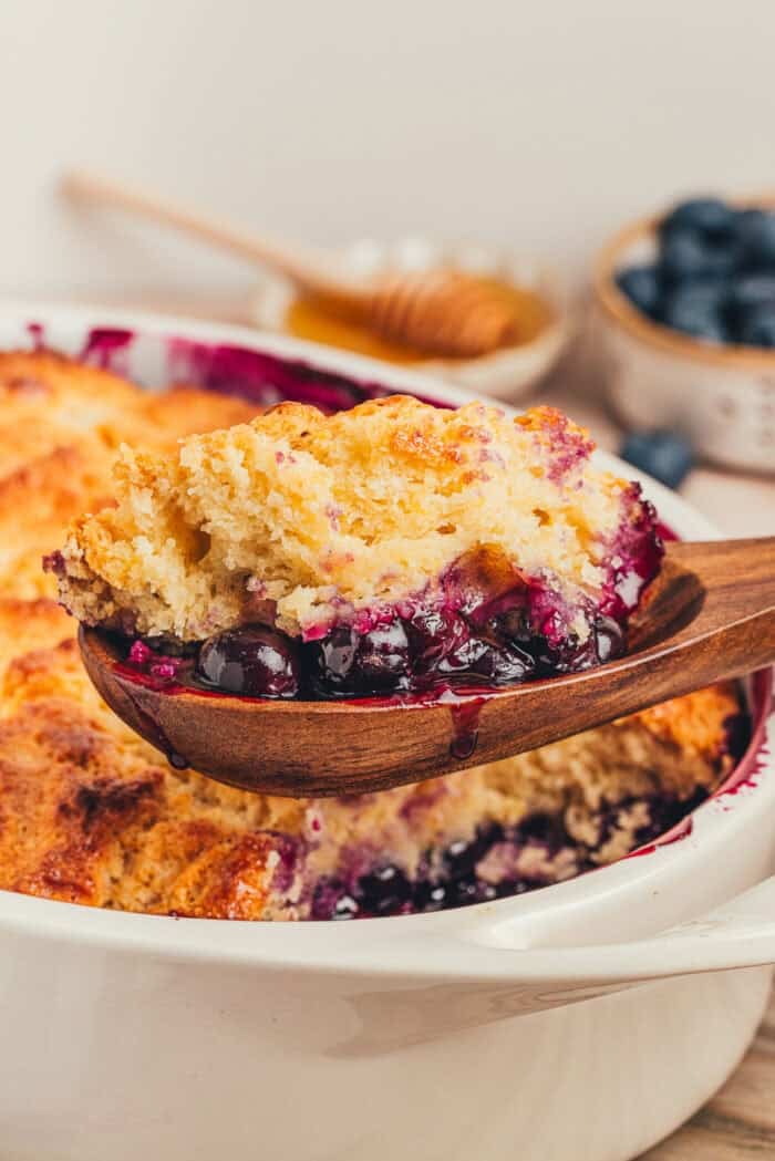 A scoop of blueberry cobbler being scooped out of the cobbler.
