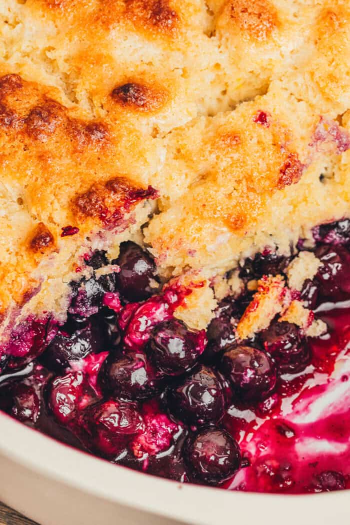A bowl with a serving of blueberry cobbler and a spoon.