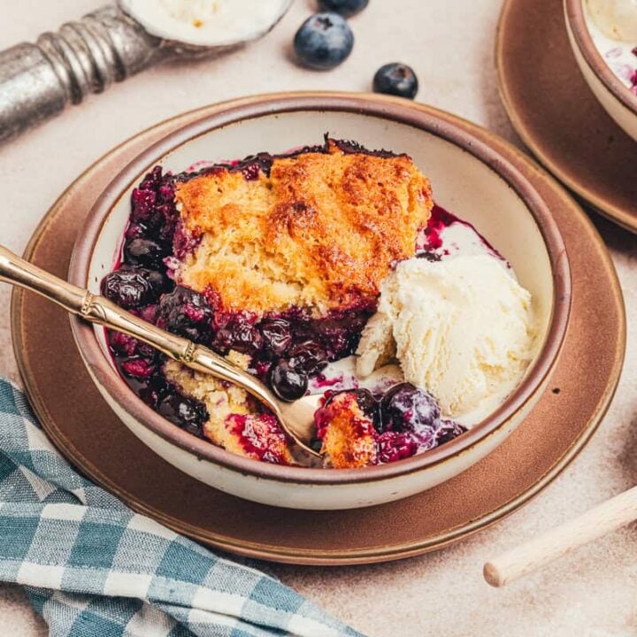 A plate with a serving of honey Sweetened blueberry cobbler.