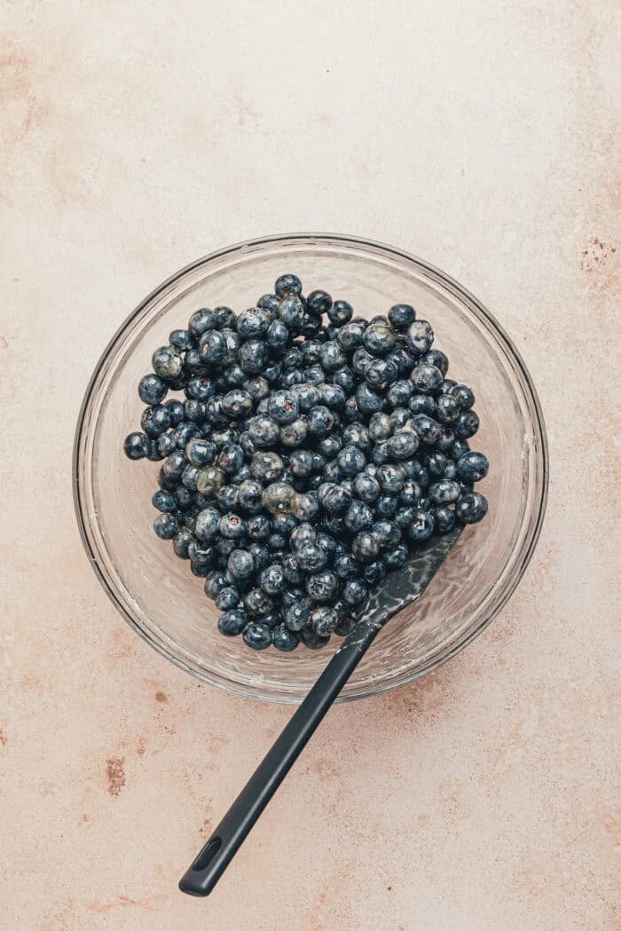 Blueberries in a bowl with a spatula.