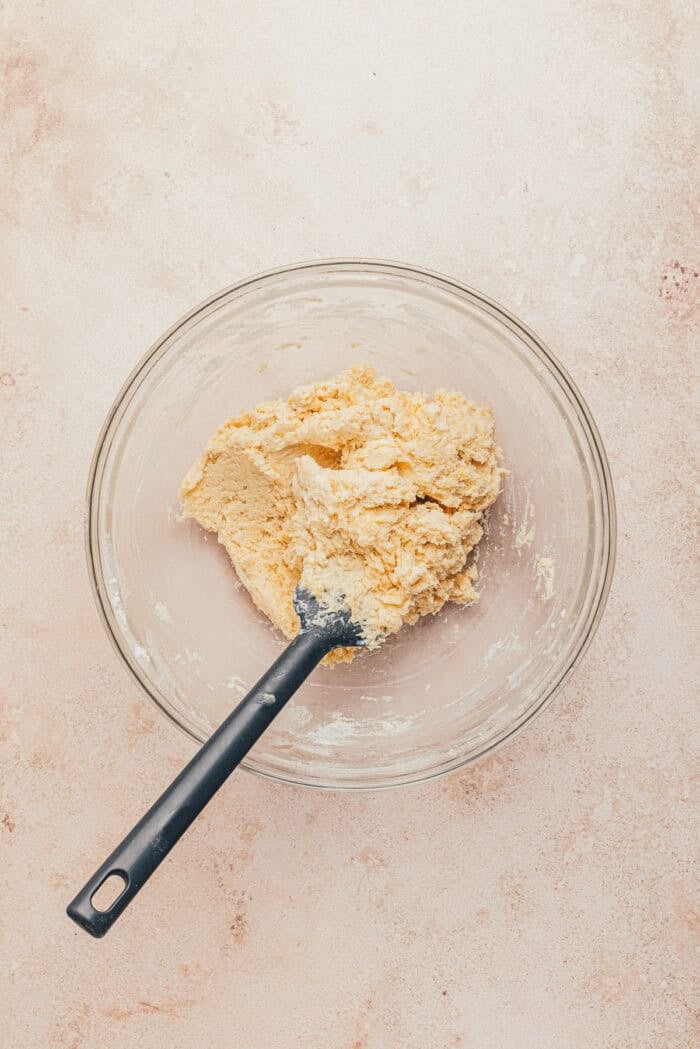 In a glass bowl, the combined cobbler dough with a spatula.
