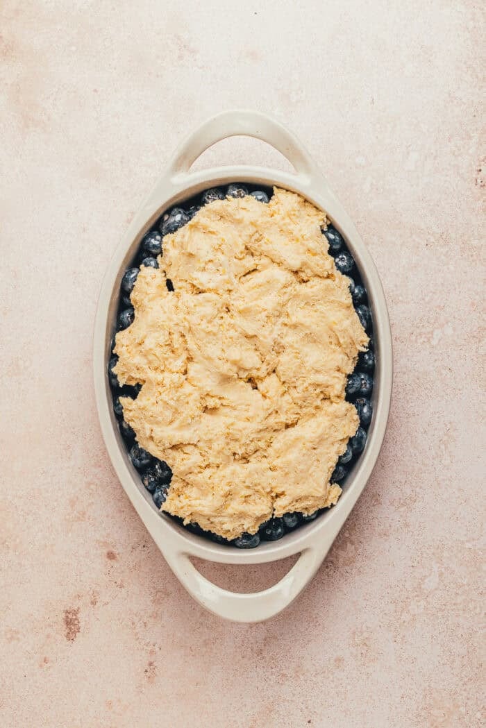 The cobbler dough dropped over the blueberries in an oval dish.