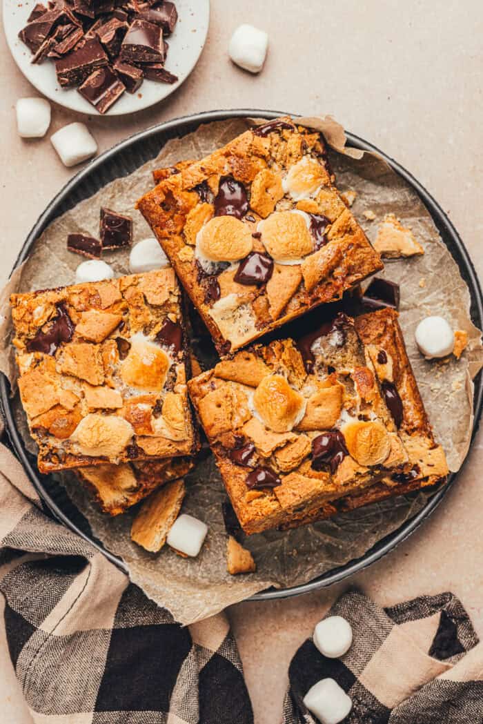 Slices of s'mores blondies on a metal cake pan bottom.