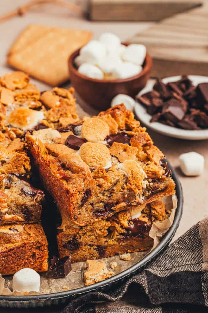 Slices of s'mores blondies on a metal cake pan bottom.