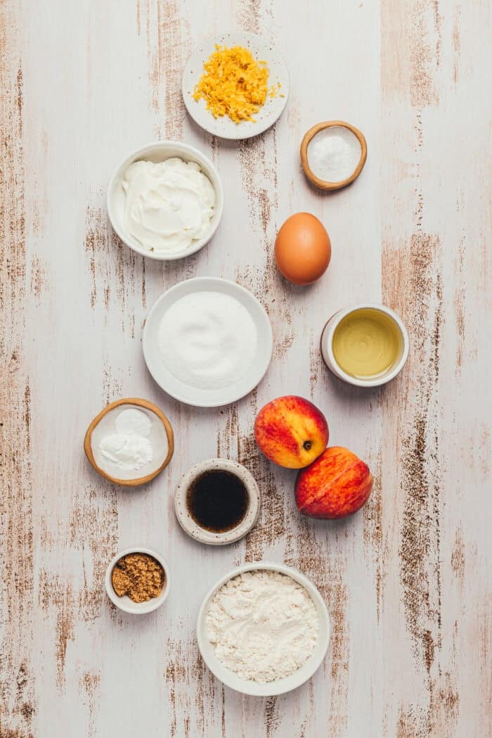 Various bowls containing the ingredients to make a homemade peach cake.