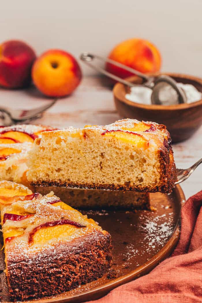 A slice of peach cake being lifted with a spatula.