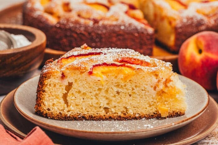 A slice of homemade peach cake on a plate.
