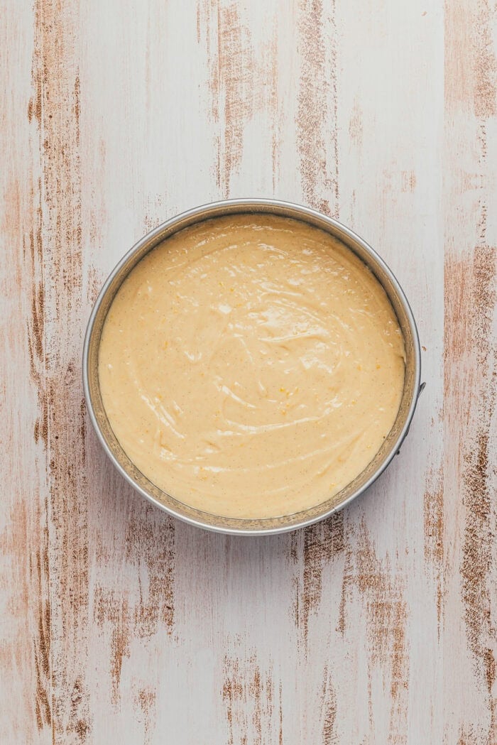 Peach cake batter in a round cake pan.