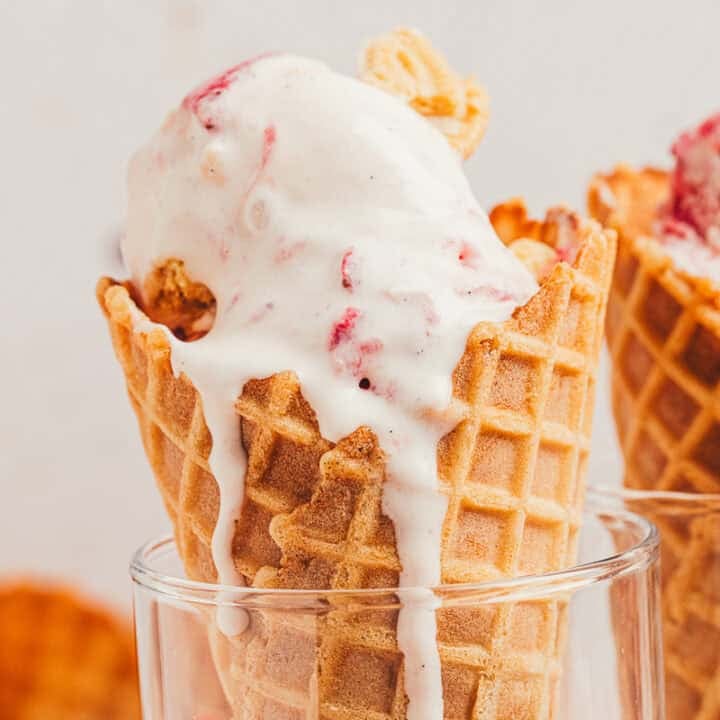 Two ice cream cones filled with homemade strawberry cookies and cream ice cream.