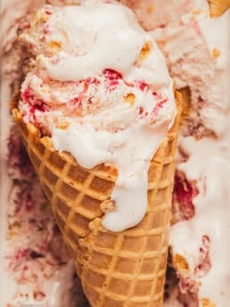 An ice cream cone with ice cream with strawberries.