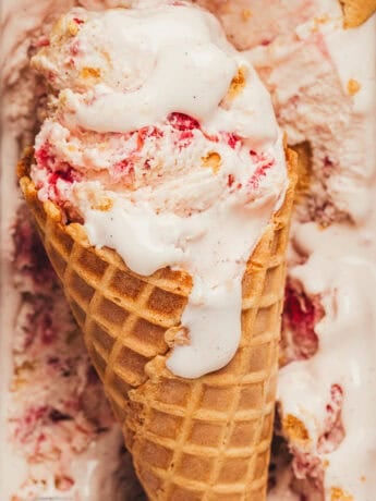 An ice cream cone with ice cream with strawberries.
