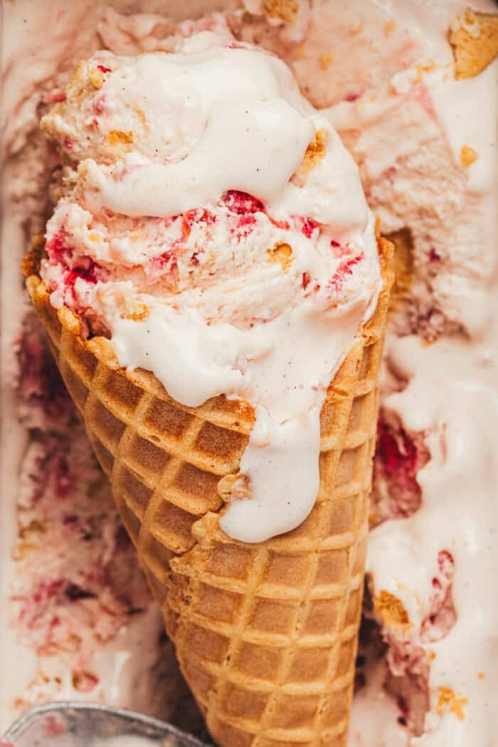 An ice cream cone with ice cream with strawberries.