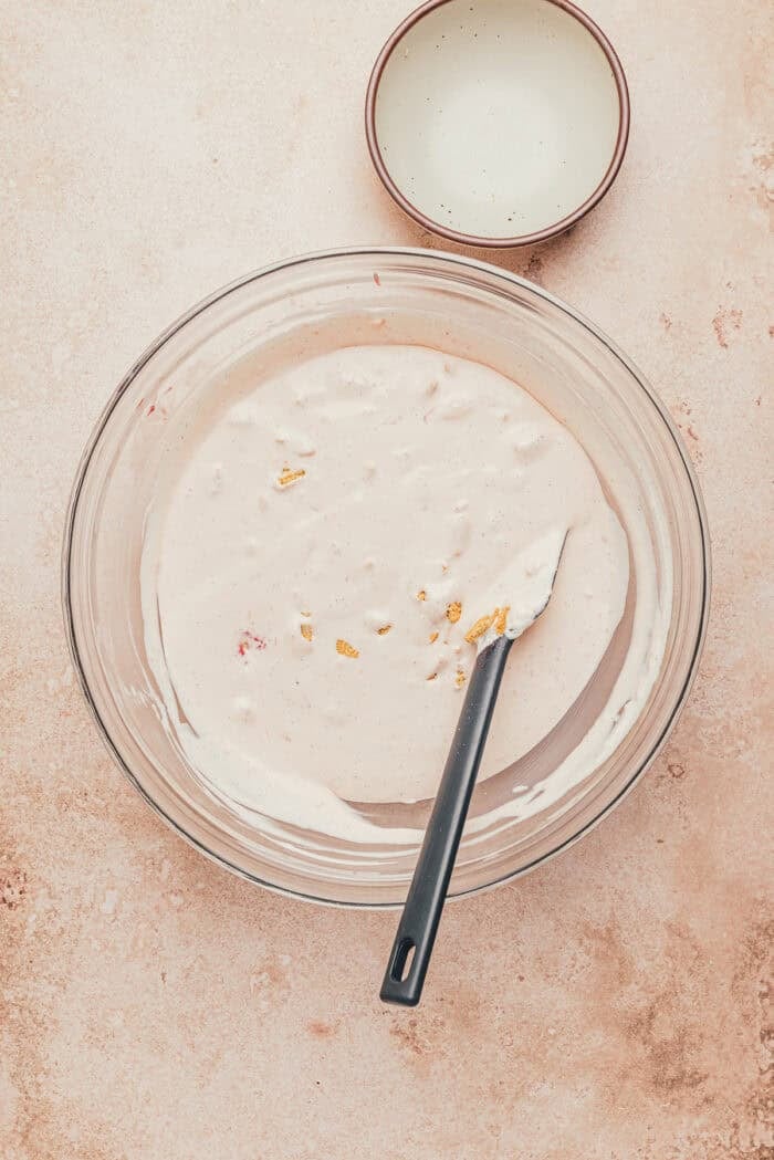 The ice cream mixture in a large glass bowl before freezing with a spatula.