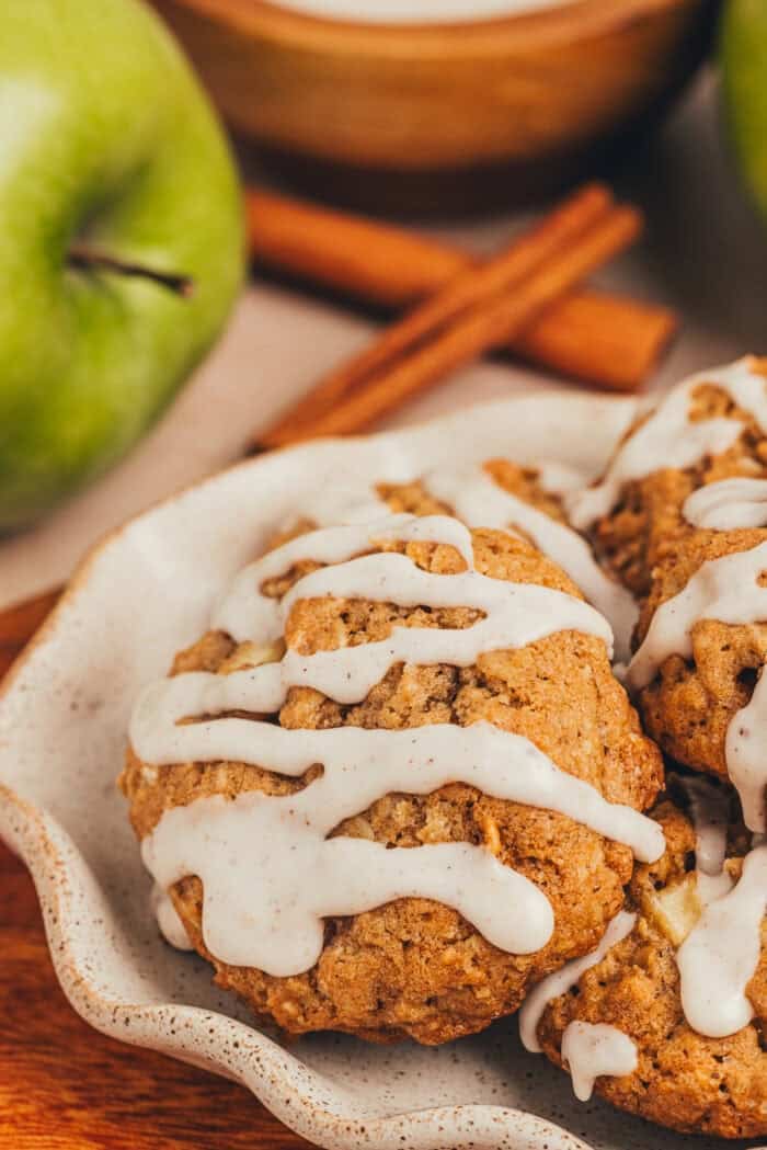 Three iced cinnamon apple oatmeal cookies on a plate.
