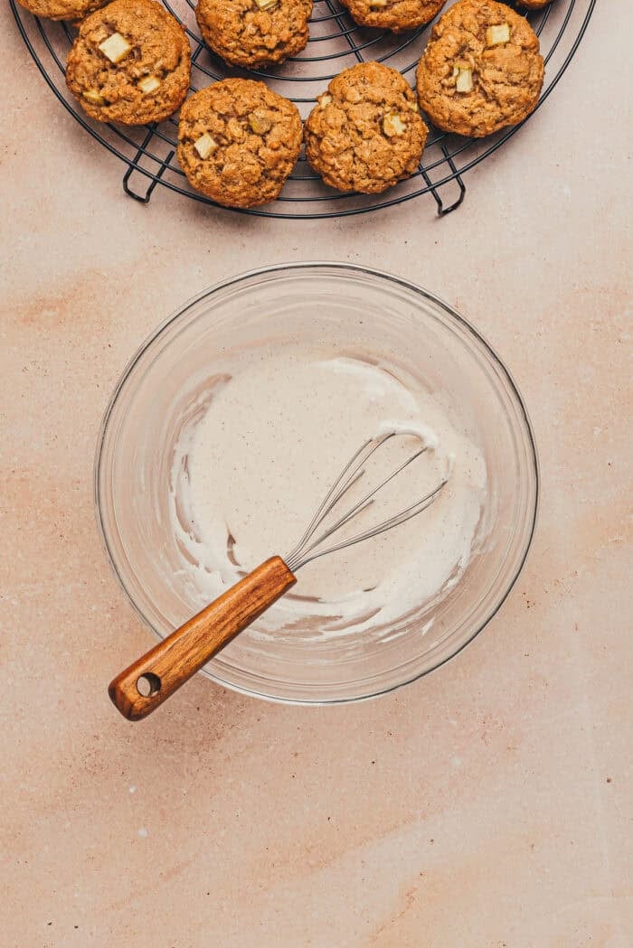 A glass bowl with the icing and a whisk.