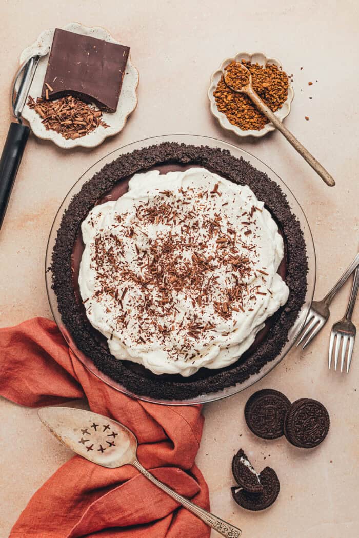 A no bake chocolate pie in a pie plate with smaller plates filled with garnishes.