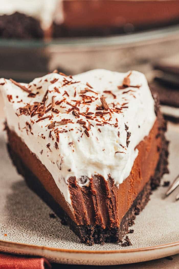 A slice of no bake chocolate pie on a small plate with a bite taken out of it.