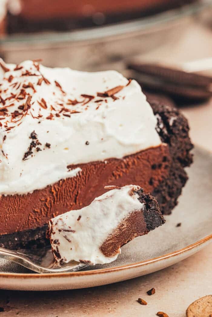 A slice of no bake chocolate pie on a small plate with a fork with a bit of the pie on it.