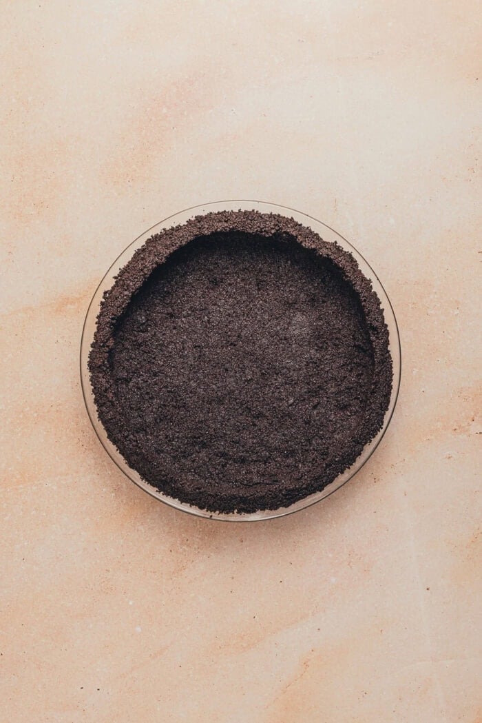 A pie plate with Oreo crumbs pressed into the plate.