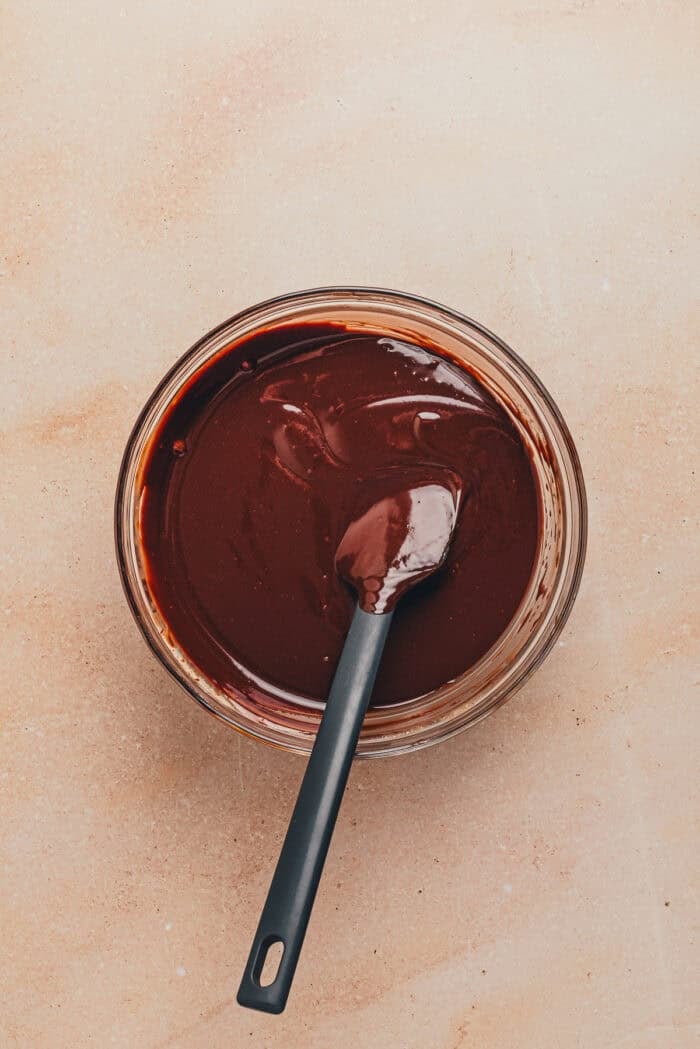 The heavy cream mixture mixed with the chocolate chucks in a glass bowl with a spatula.