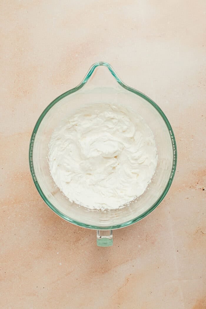 A glass mixing bowl with the whipped heavy cream topping.