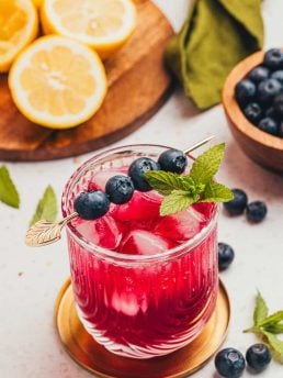 A blueberry gin fizz cocktail garnished with blueberries and mint.